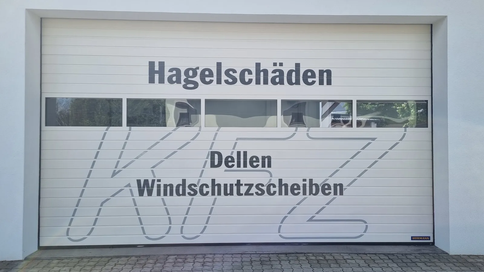 Werkstatttor mit den Beschriftungen Hagelschäden, Dellen und Windschutzscheiben